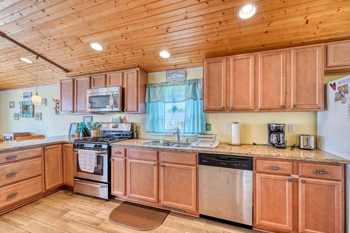 A kitchen with wooden cabinets, a stainless steel stove, a dishwasher, and a microwave.