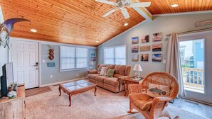 A spacious living room with a wooden ceiling, a large window, and a comfortable seating area.