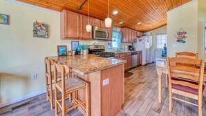A kitchen with wooden cabinets, a granite countertop, and a central island with bar stools.