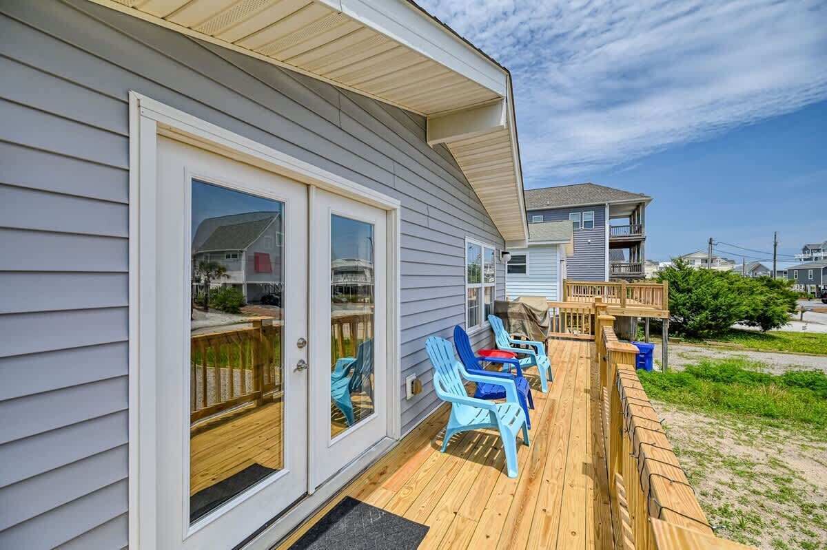 A house with a deck, sliding glass doors, and a small outdoor seating area with chairs.