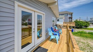 A house with a deck, sliding glass doors, and a small outdoor seating area with chairs.