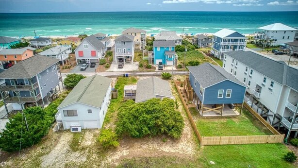 A coastal residential area with houses, a beach, and the ocean in the background.
