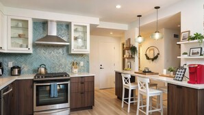 Una cocina moderna con una isla central, electrodomésticos integrados y un comedor con sillas blancas.