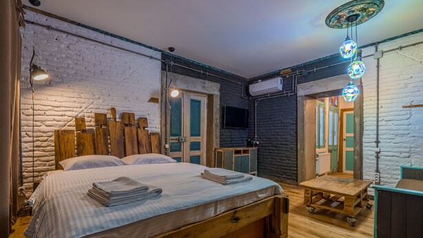 Ein Schlafzimmer mit einem hölzernen Bett, einem kleinen Tisch und einem Fernseher an der Wand.