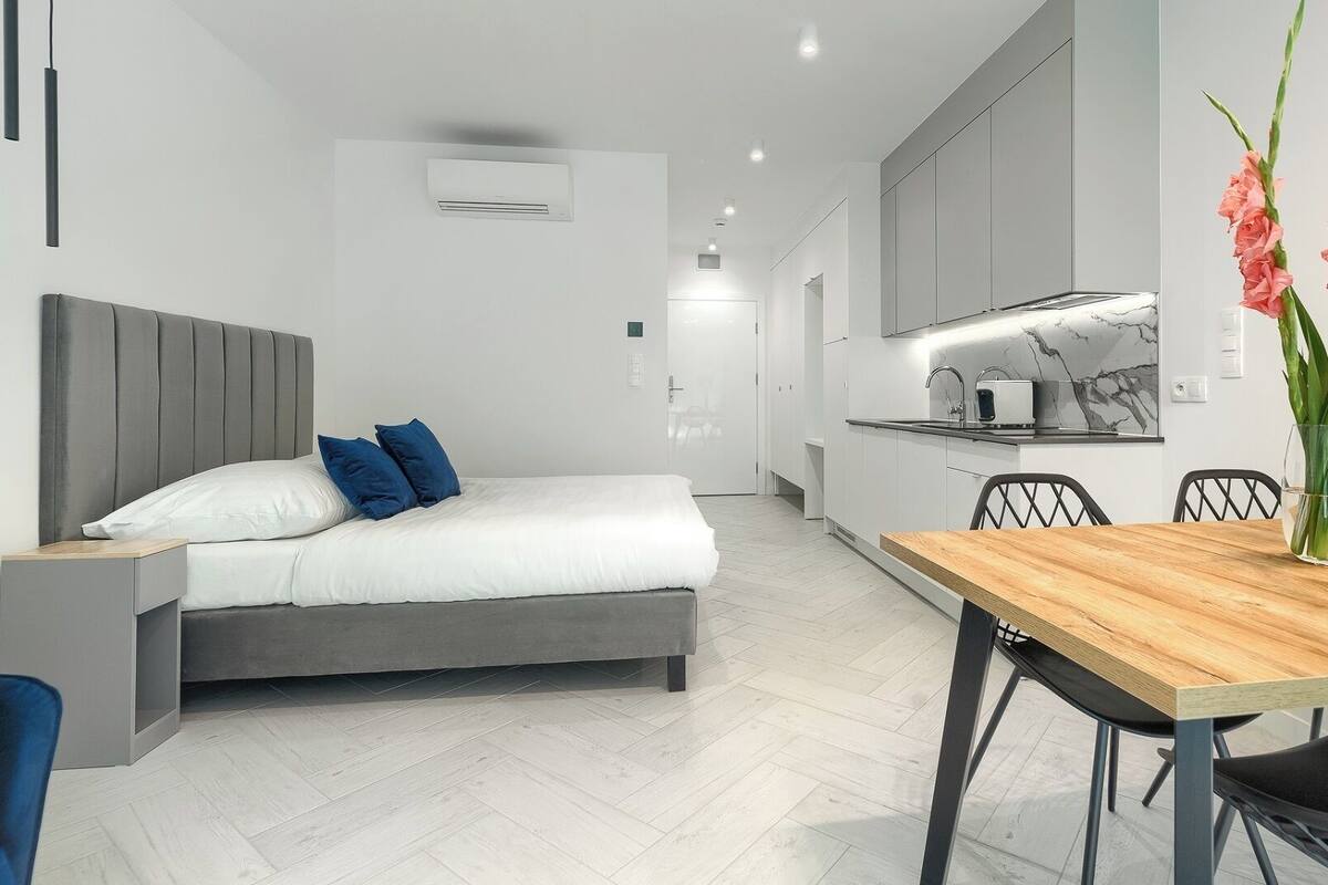 Een moderne hotelkamer met een bed, nachtkastje en een zithoek met een tafel en stoelen.
