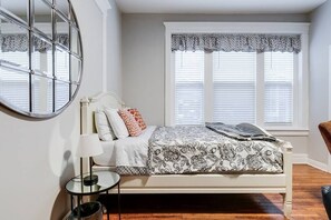 Classic bedroom with a bed, round mirror, and side table.