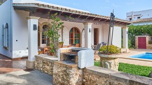 Une villa dotée d’une cheminée en pierre, d’un espace salon extérieur et d’une piscine.