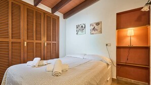 Un lit bien fait, agrémenté de serviettes pliées, de portes coulissantes en bois et d’œuvres d’art accrochées au mur.