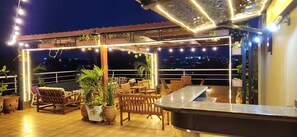 An outdoor patio area with wooden furniture, potted plants, and string lights. - Acquah Place Residences (Accra)