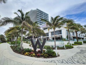 A modern hotel with a prominent 'W' sign, palm trees, and a multi-story building in the background.