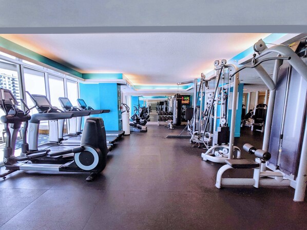 Een sportschool met loopbanden, elliptische trainers en gewichten.