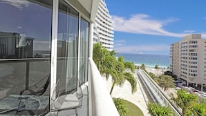 Een balkon met uitzicht op de oceaan, een stoel en een gebouw met een witte gevel.
