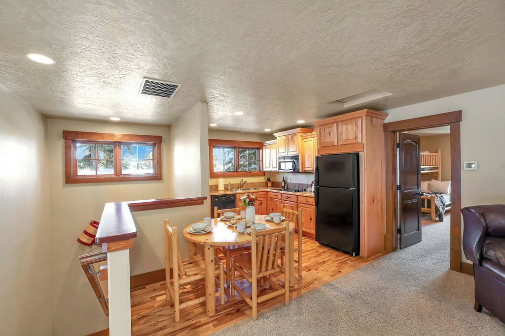 A spacious kitchen with wooden cabinets, a black refrigerator, and a dining area with a wooden table and chairs.