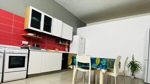 Een keuken met witte kastjes, een fornuis en een eettafel met stoelen.