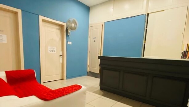 Een hotellobby met een witte bank, een zwarte balie en blauwe wanden.