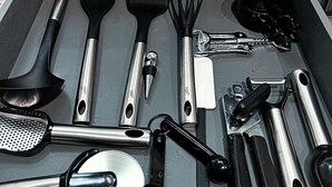 Un tiroir de cuisine contenant divers ustensiles et outils, notamment une spatule, un fouet et une râpe.