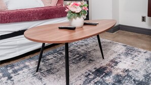 Une chambre d’hôtel moderne avec un canapé rouge, une table basse en bois, un vase de fleurs et une lampe.