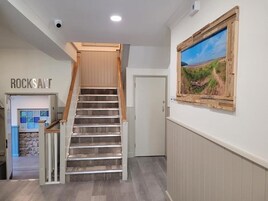 Una escalera con barandillas de madera, una puerta en la parte superior y un cuadro con un paisaje colgado en la pared.