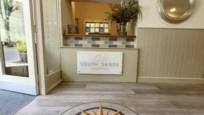 Un área de recepción con un letrero que dice "South Sands Reception" y un diseño de brújula en el suelo.