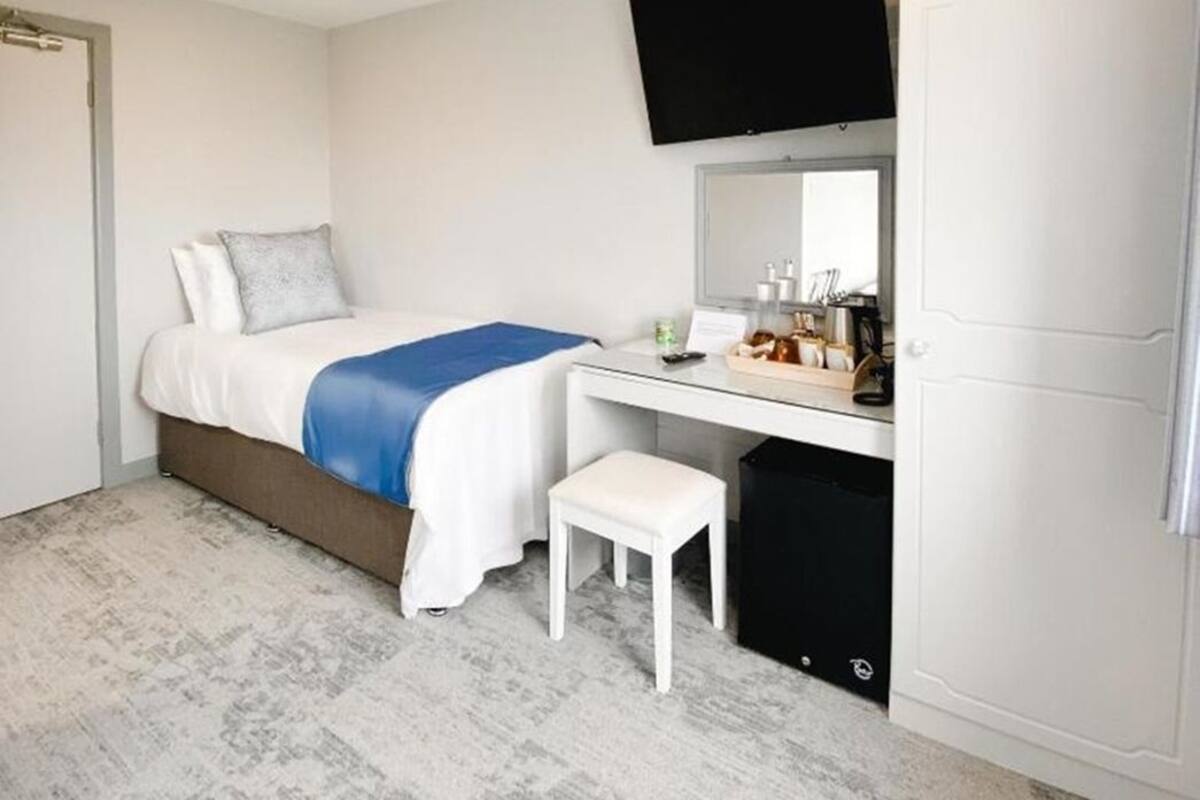 Una habitación de hotel con cama, escritorio, televisor y armario.