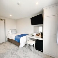 Una habitación de hotel con cama, escritorio, televisor y armario.