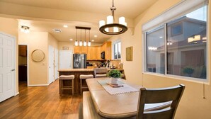 Una cocina moderna con armarios de madera, un refrigerador de acero inoxidable y una zona de comedor con una mesa y sillas.