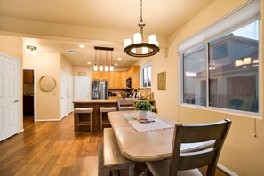 A modern kitchen with wooden cabinets, a stainless steel refrigerator, and a dining area with a table and chairs.