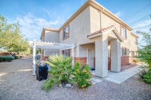 A two-story house with a covered patio and a gravel driveway.