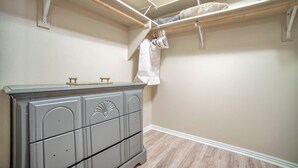 Una habitación con un aparador gris, un perchero con ropa y suelo de madera.