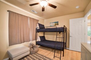 A bunk bed with a ceiling fan, a sofa, a door, and a painting on the wall. - Mesquite 2BR Townhome with Pool & Gym Access (Mesquite)