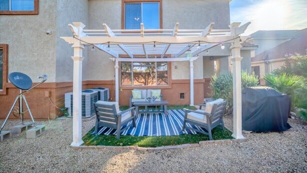 Un patio techado con mobiliario exterior, una antena parabólica y una parrilla cubierta.