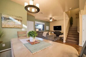 A spacious living area with a dining table, sofa, and a staircase. - Mesquite 2BR Townhome with Pool & Gym Access (Mesquite)