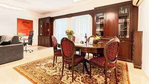 A dining area with a round table, four chairs, a rug, and a cabinet with glass doors.