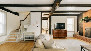 A spacious living room with a wooden staircase, a fireplace, and a television. - Quaint, Vintage Reno in Manheim (Manheim)