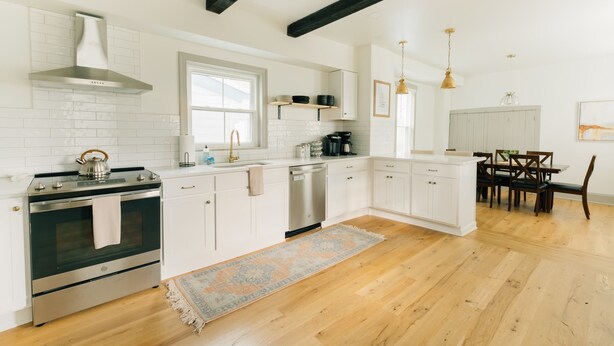 A modern kitchen with white cabinetry, stainless steel appliances, and a wooden floor. - Quaint, Vintage Reno in Manheim (Manheim)
