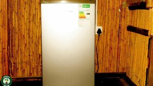 Un refrigerador blanco con una etiqueta de eficiencia energética, un enchufe y una pared de madera.