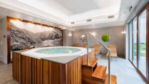 Un spa moderno con hidromasaje, asientos de madera y un mural con vistas a la montaña.