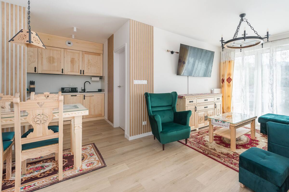 Una sala moderna con un sillón verde, un sofá color turquesa y una mesa de comedor de madera.