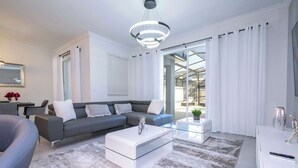 A modern living room with a grey sofa, a white coffee table, and a glass coffee table. - Stunning 4 Bd w/ Pool @ Storey Lake Resort 2613 (Kissimmee)
