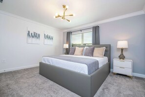 Une chambre à coucher avec un lit, des tables de chevet, une fenêtre avec des rideaux et un luminaire au plafond.