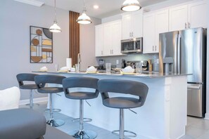 A modern kitchen with white cabinets, stainless steel appliances, and a central island with bar stools.
