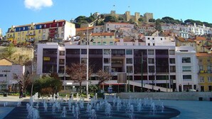 A public square with a fountain, surrounded by colorful buildings and a castle in the background. - Apartamento 73 com Terraço (Lisbon)
