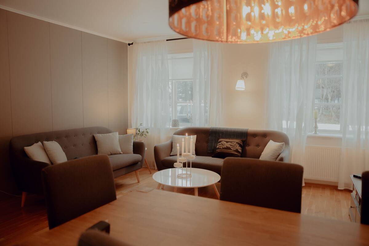 A modern living room with a sofa, chairs, a coffee table, and a lamp.