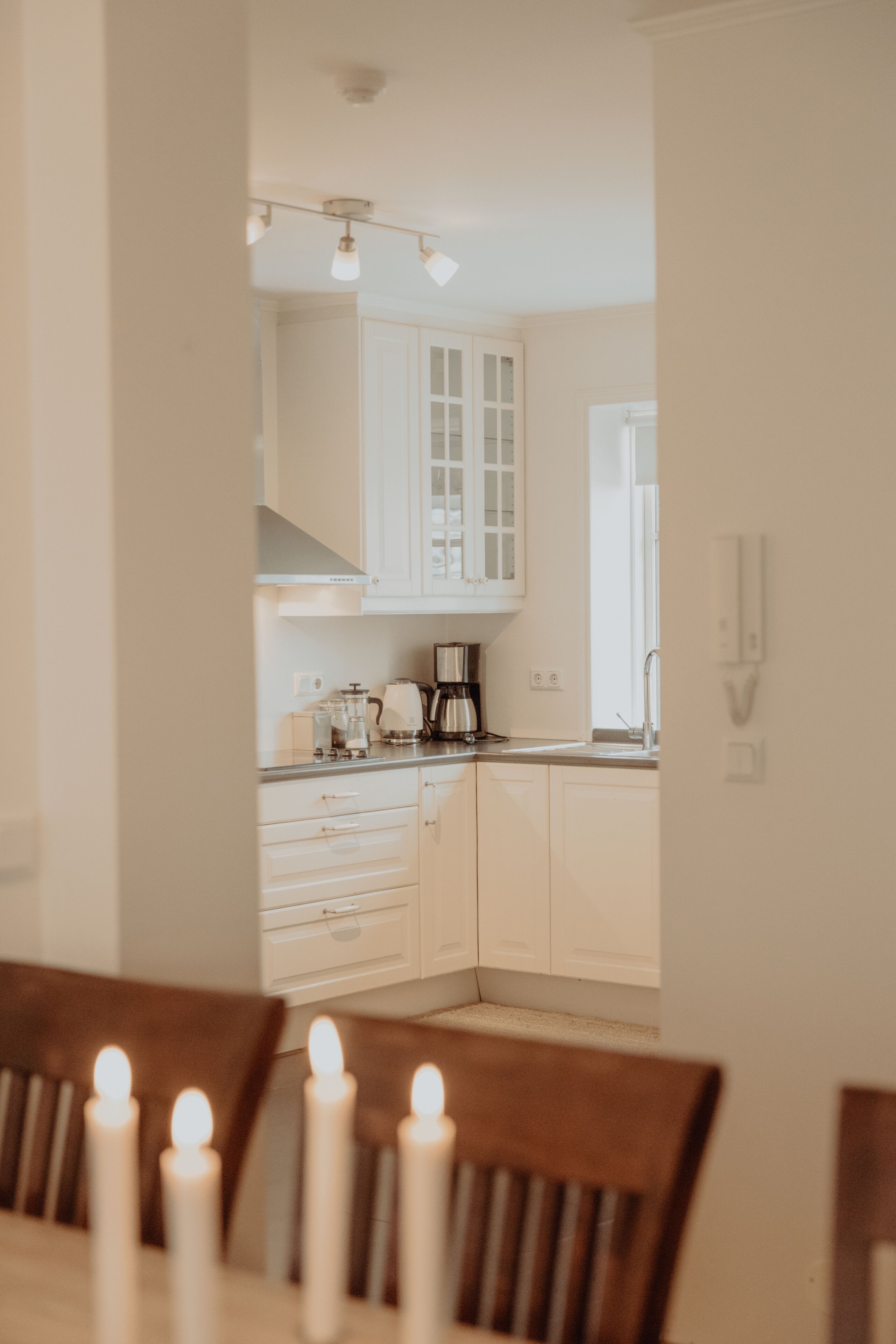 Una cucina moderna con mobili bianchi, una macchina da caffè e un'area pranzo con candele.