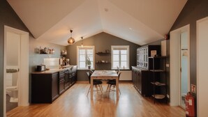 A modern kitchen with a wooden table, black cabinets, and a large window.