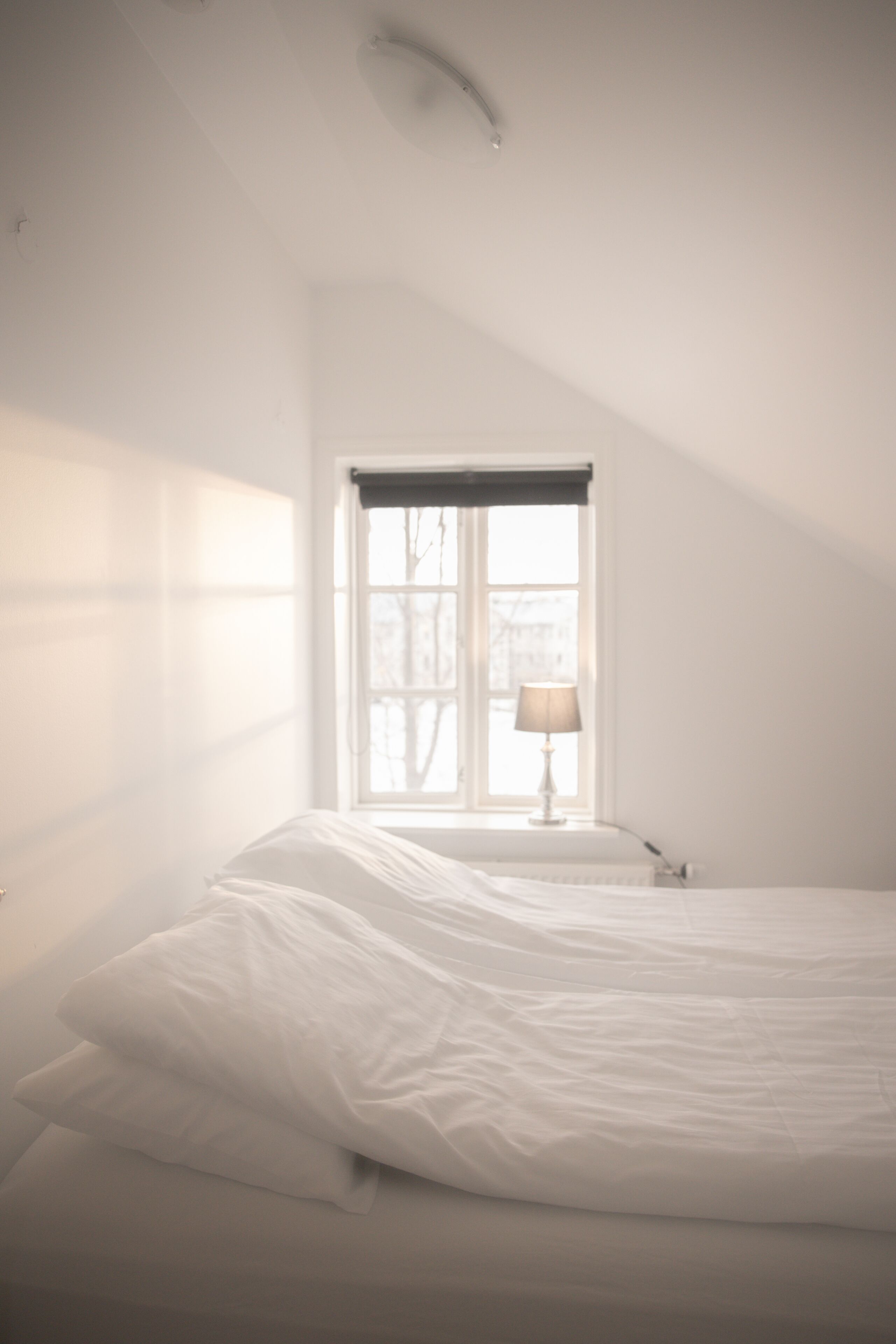 Une chambre à coucher avec un lit, une fenêtre donnant sur un beau paysage et une lampe sur une table de chevet.