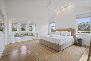 Een slaapkamer met een groot bed, ingebouwde zitplaatsen en meerdere ramen.