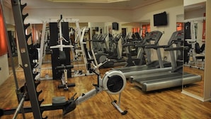 Ein Fitnessstudio mit verschiedenen Trainingsgeräten, darunter Laufbänder, Crosstrainer und Kraftgeräte.