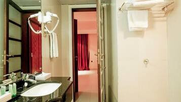 Baño de hotel con lavamanos negro, espejo, secador de pelo y perchero para toallas.