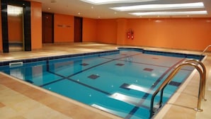 Ein Schwimmbecken mit klarem, blauem Wasser, umgeben von orangefarbenen Wänden und einem gefliesten Boden.